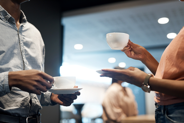 Ein Mann und eine Frau im Gespräch mit Kaffeetassen in den Händen