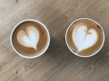 Zwei Becher mit Kaffee und Milchschaum in Herzform, Ansicht von oben